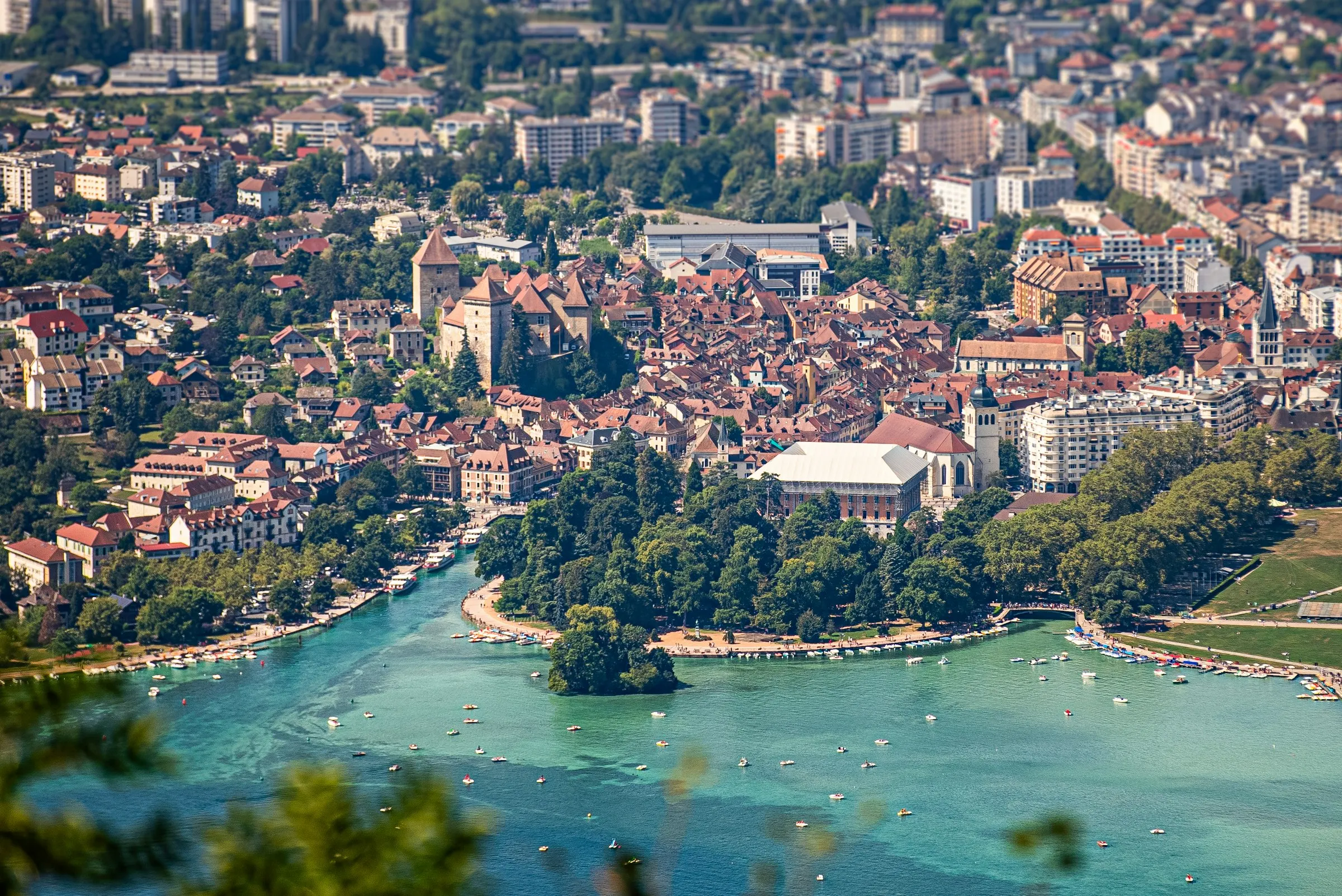 Aerial view of Annecy old town and its chateau above the turquoise Lake Annecy, ringed by the Alps