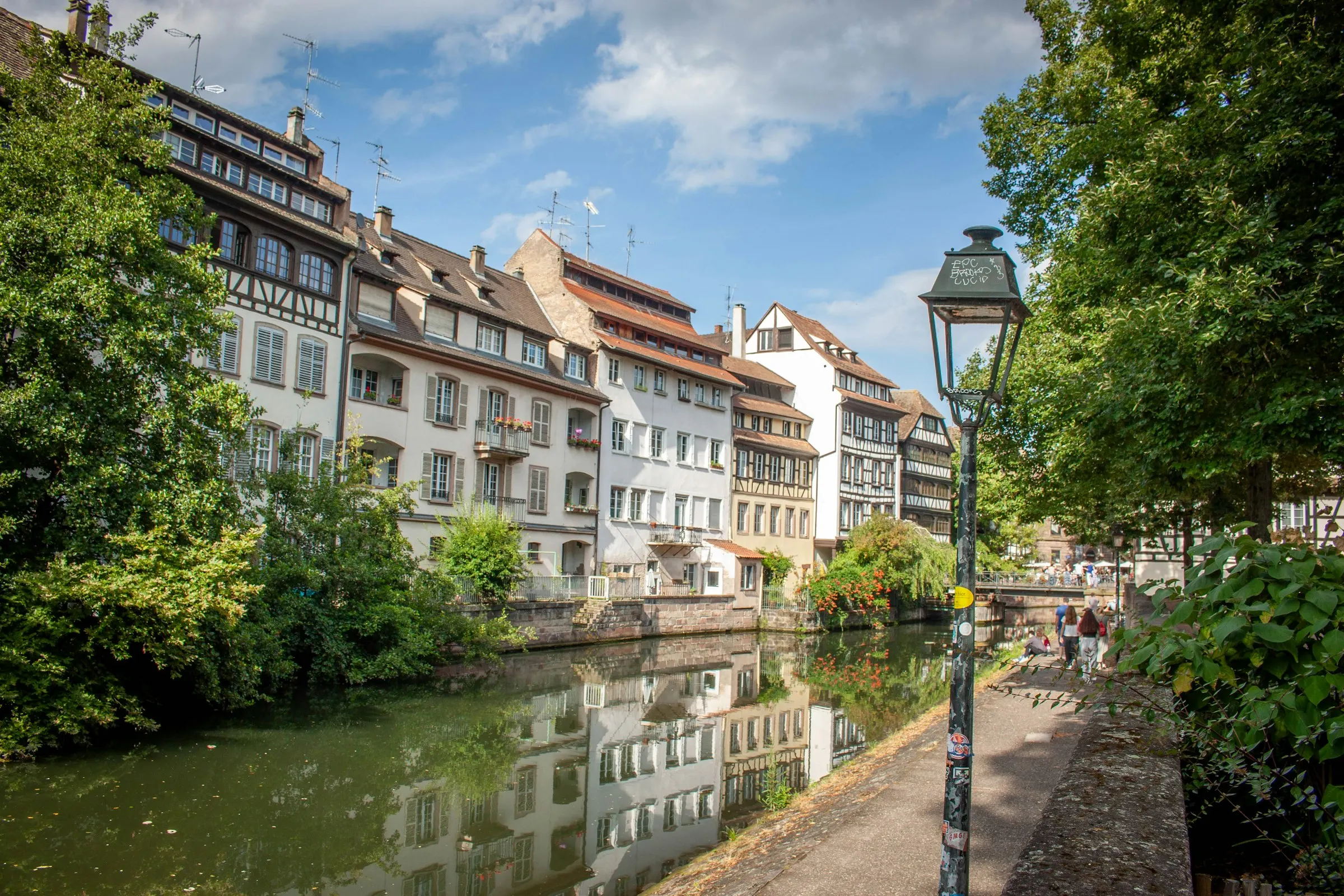 A canal-side lane in Strasbourg Petite France, lamppost and greenery along the water