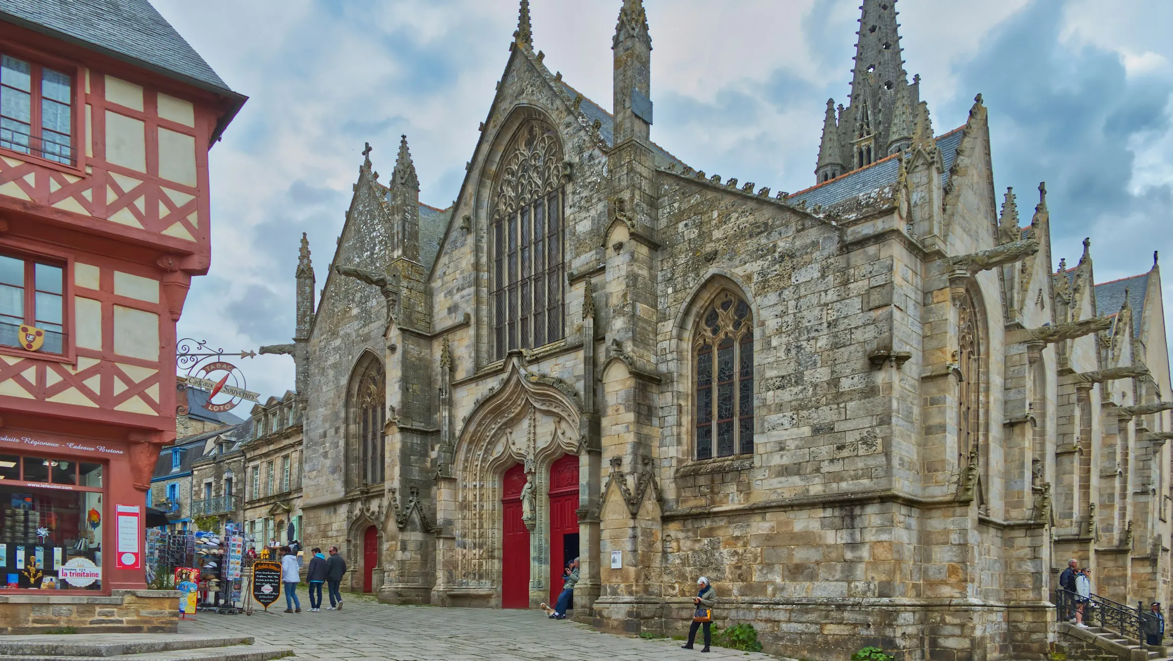 The Flamboyant Gothic Cathedrale Saint-Pierre de Vannes rising over the paved Place Saint-Pierre, with a red half-timbered Breton gift shop on the corner
