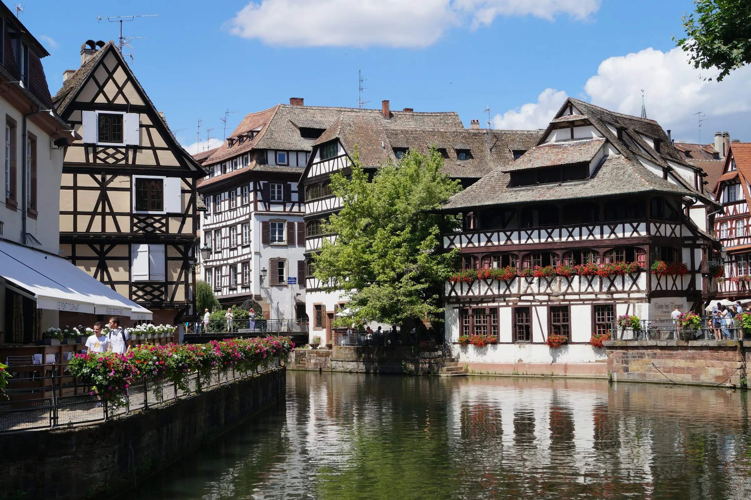 Strasbourg Petite France quarter, half-timbered houses and a flower-lined footbridge reflected in the Ill canal