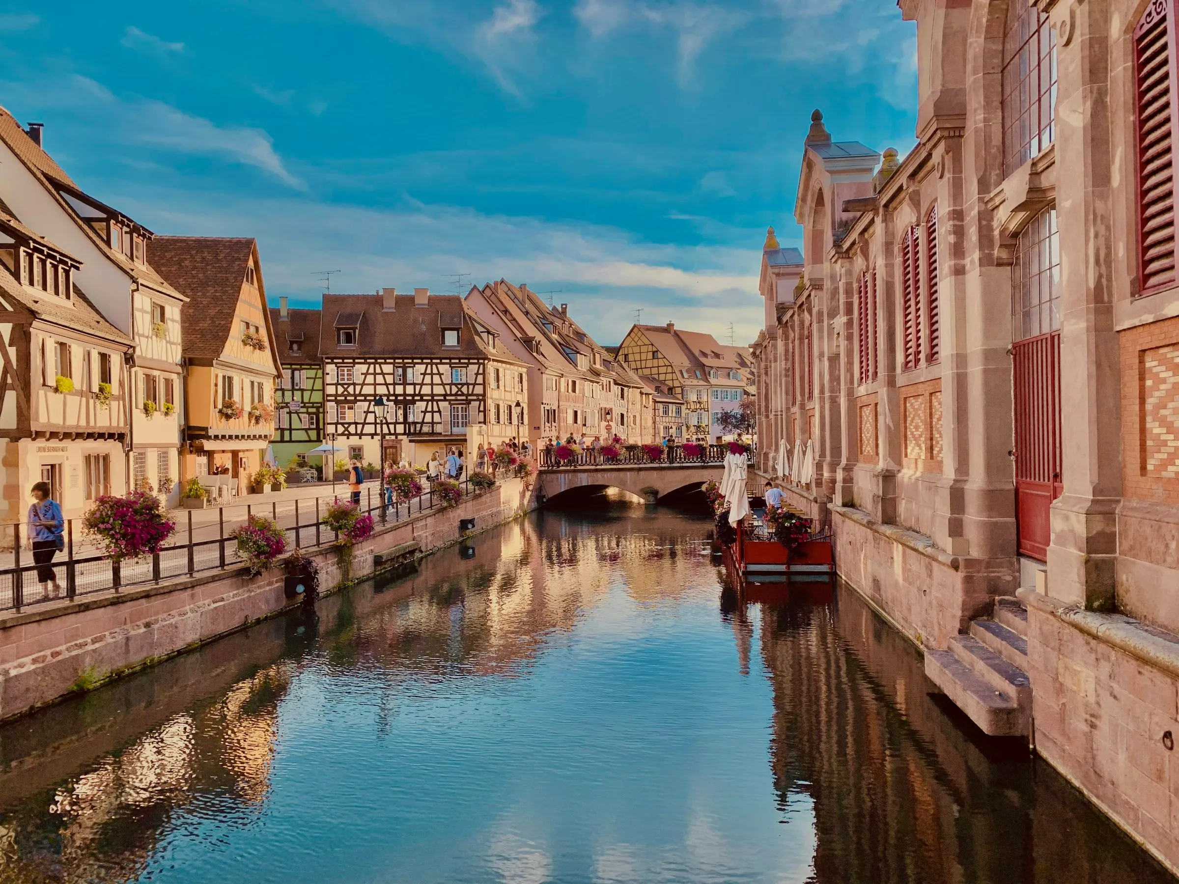 La Petite Venise in Colmar at golden hour, half-timbered houses and flower-lined quais reflected in the canal